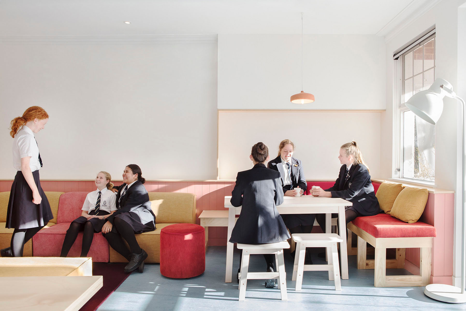 group of girls in school uniform talking at a table and couch area