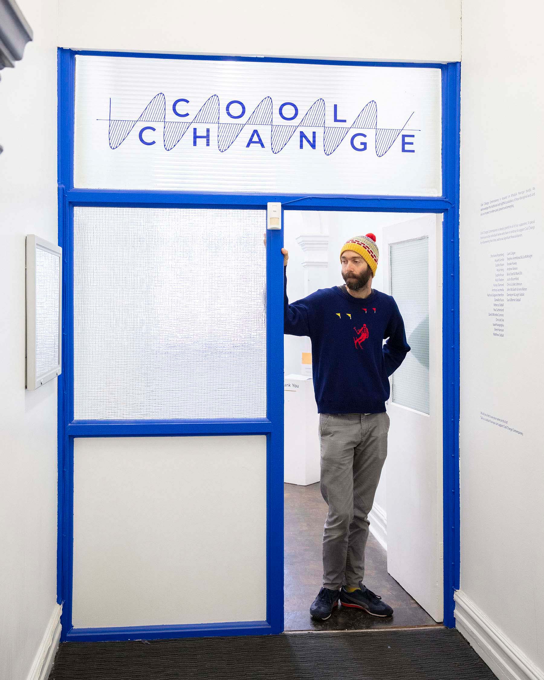 man stands in blue doorway of art gallery