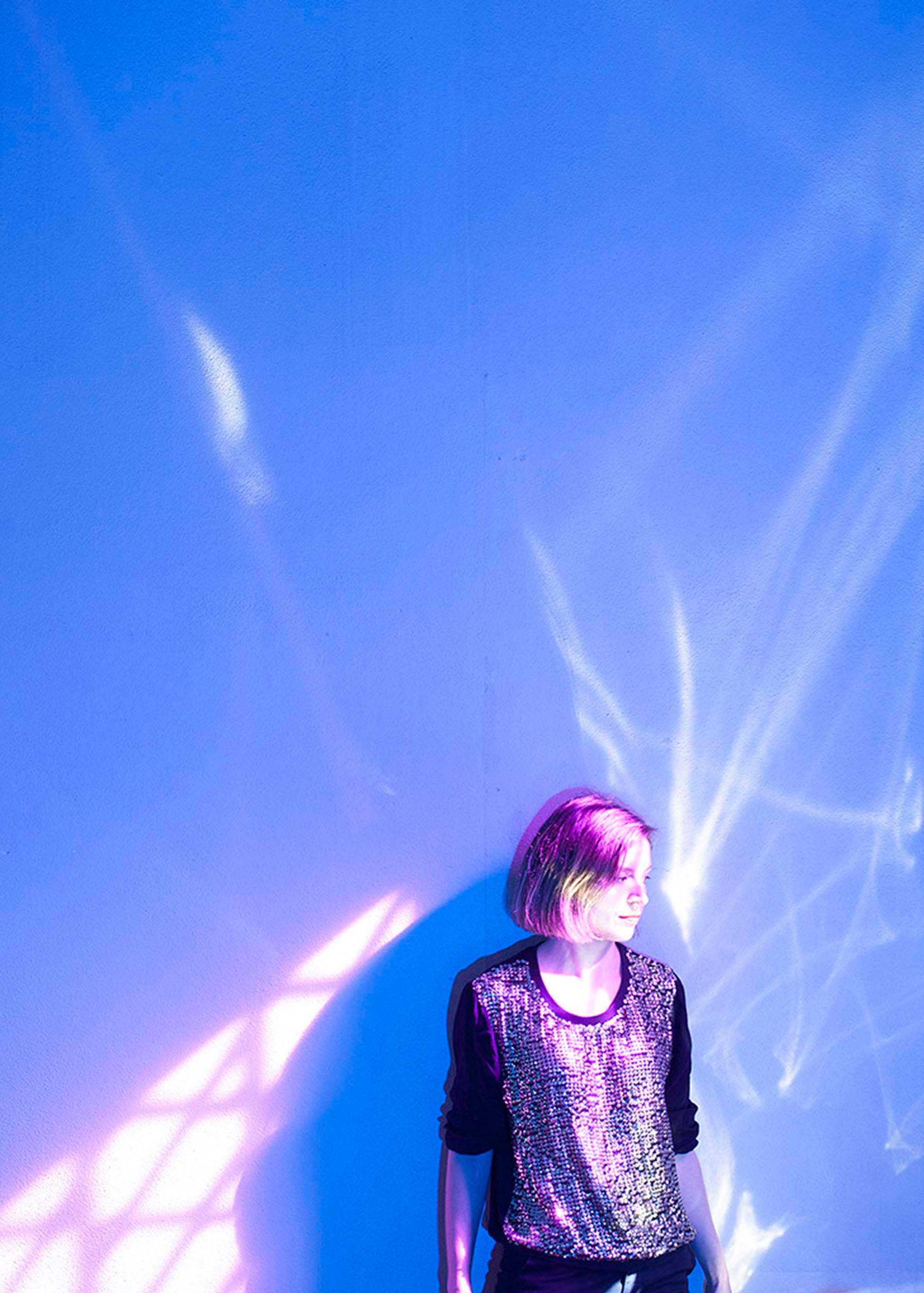 woman looking to the side with various coloured light aroudn her.